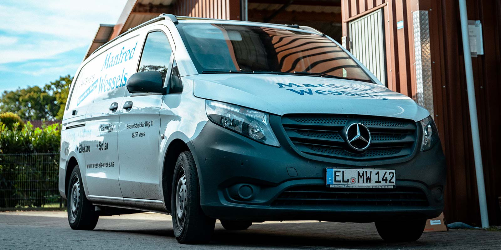 Ein Mercedes-Benz Transporter steht vor einem Gebäude, mit der Aufschrift 'Manfred Wessels' auf der Seite.