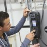 Zwei Männer arbeiten gemeinsam an einem technischen Gerät Zwei Männer konzentrieren sich auf ein technisches Gerät, während einer von ihnen einen Knopf drückt und Anweisungen gibt.