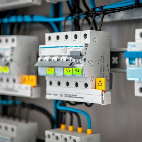 Ein elektrischer Verteiler mit mehreren Schaltern und bunten Kabeln, die ordentlich angeordnet sind, zeigt moderne Technik.